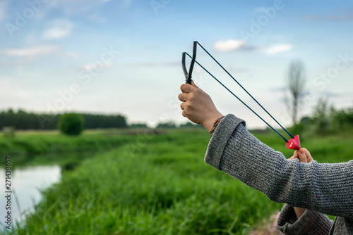 View of the hand of a man shooting from a slingshot to feed fish.