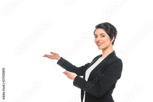 attractive mixed race businesswoman gesturing and smiling at camera isolated on white