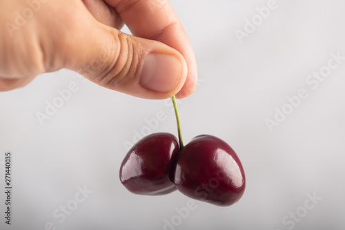 Man holds two ugly cherries with his fingers. Strange shape berries