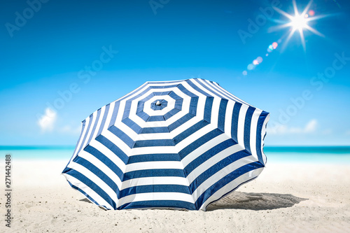 Summer background of umbrella with free space for your decoration on hot sand. Sunny day and ocean landscape. 