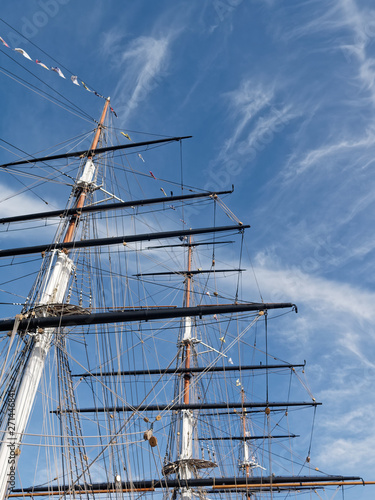 Masts and rigging of a sailing ship against a bright blue sky. Focused to the the foreground.