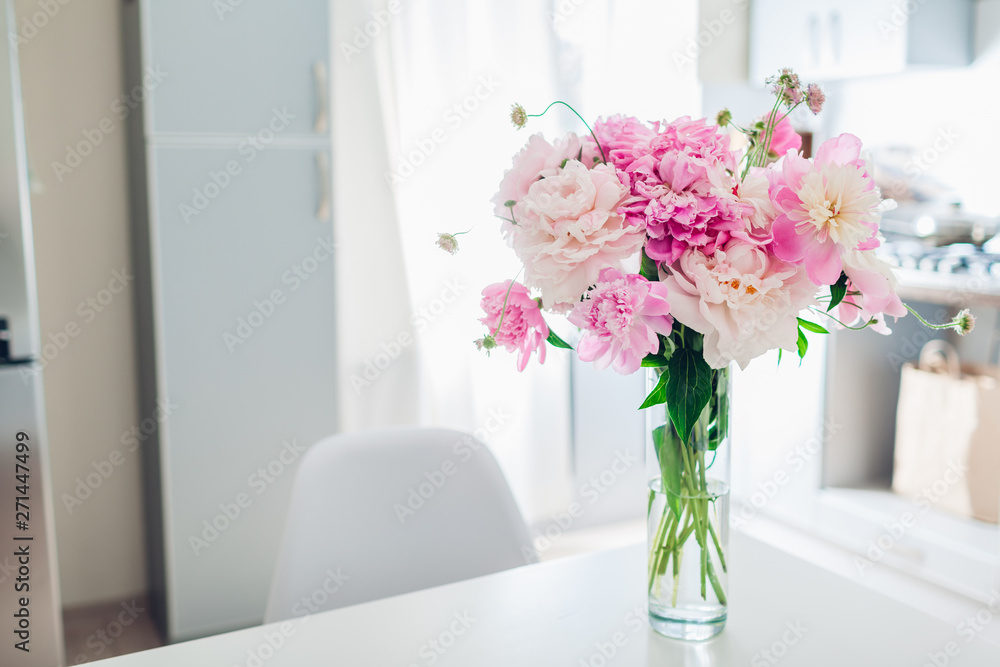 Pink peonies. Modern kitchen design. Interior of white and silver kitchen decorated with flowers. Pink peonies. Modern kitchen design. Interior of white and silver kitchen decorated with flowers.