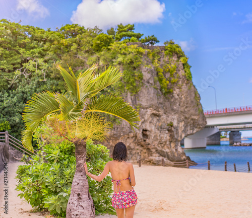 Young woman in swimsuit in front of a palm tree on the sandy beach Naminoue in Naha City in Okinawa Prefecture, Japan. photo