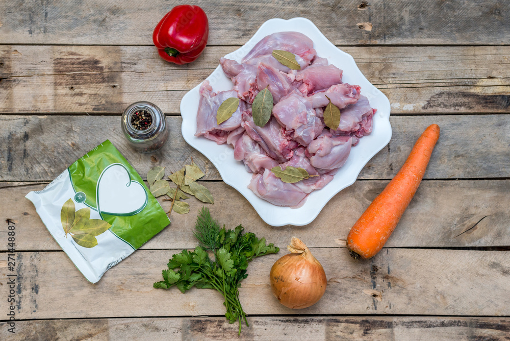Recipe for a festive meal and a healthy diet. Carcasses of domestic rabbit, cut into pieces, raw meat with spices and vegetables on the background of wooden boards. magazine cover, copy space, flatlay Recipe for a festive meal and a healthy diet. Carcasses of domestic rabbit, cut into pieces, raw meat with spices and vegetables on the background of wooden boards. magazine cover, copy space, flatlay