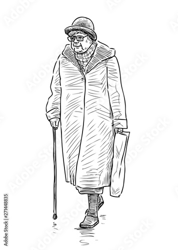 An elderly woman in a hat with a stick goes down the street