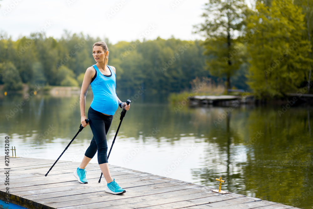 Pregnant woman nordic walking outdoor, exercises during pregnancy