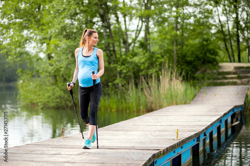Pregnant woman nordic walking outdoor, exercises during pregnancy