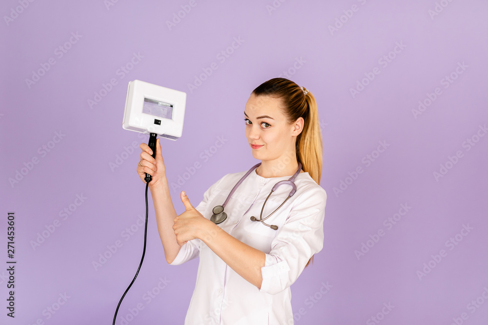 Young female doctor in white uniform with phonendoscope on her neck holding wood's light on purple background with space for text. Healthcare concept Young female doctor in white uniform with phonendoscope on her neck holding wood's light on purple background with space for text. Healthcare concept