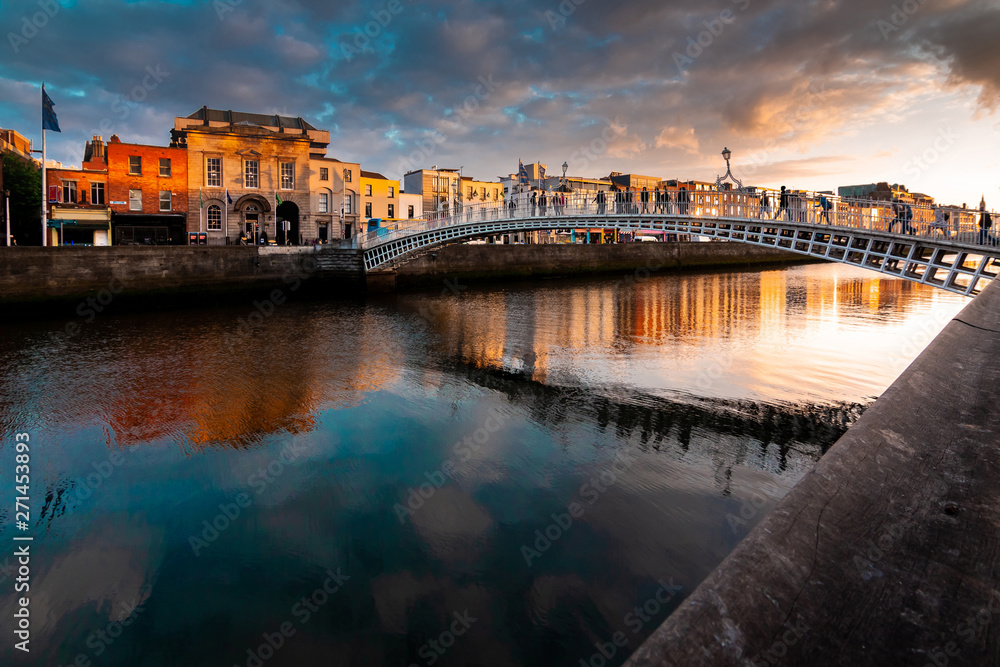 Obraz premium Most Ha'penny znajduje się nad rzeką Liffey o zachodzie słońca, Dublin, Irlandia