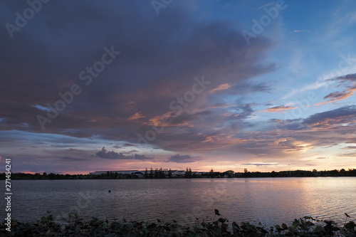 Lake view evening of dark clouds moving above reservoir with yellow sun light and cloudy sky background  sunset at Krajub Reservoir  attraction in Ban Pong  Ratchaburi  Thailand.