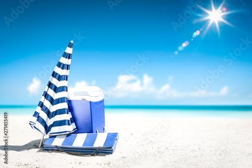 beach fridge on sand with umbrella and free space for your decoration. Summer landscape of ocean and blue sky. 