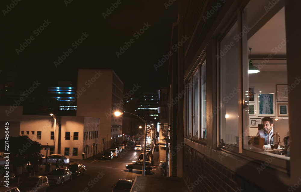 Smiling young businessman working in his office at night