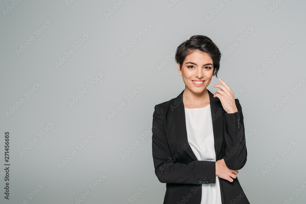 cheerful mixed race businesswoman in black formal wear smiling at camera isolated on grey cheerful mixed race businesswoman in black formal wear smiling at camera isolated on grey