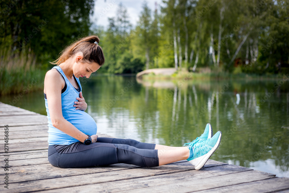 Pregnant woman exercising outdoor and resting