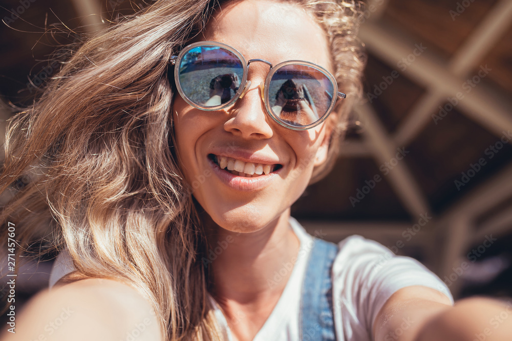 Close up portrait of a beautiful cheerful young female student taking a selfie or talking on video during a vacation on the sea on a sunny hot summer day. The concept of rest and relaxation