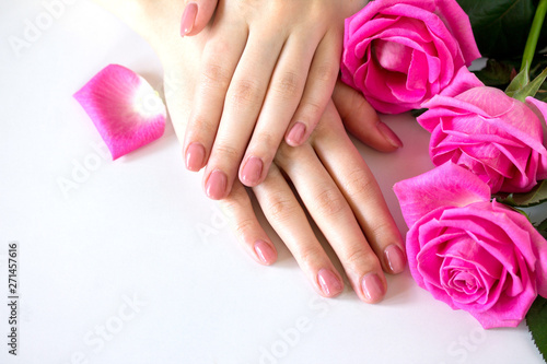 Beautiful manicured woman s nails with pink polish isolated. Nails care. Manicure  pedicure beauty salon. Beautiful rose red blossoms. Free space for your text.