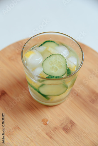 glass of water with cucumber on wooden background