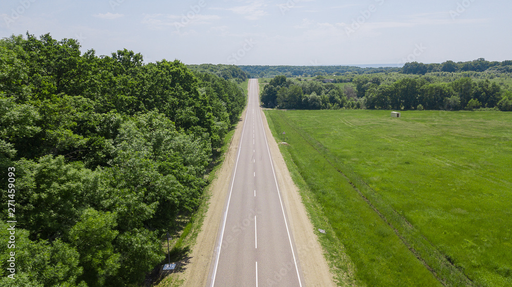 Scenic country road between dense forest and fields Scenic country road between dense forest and fields