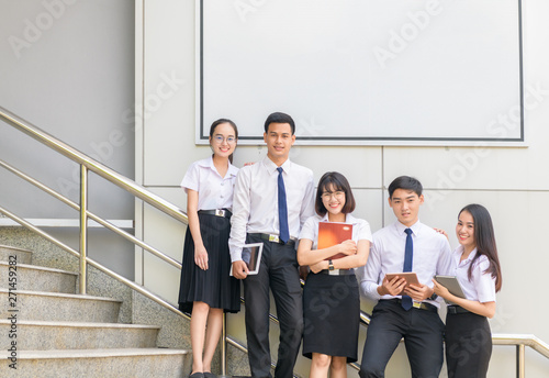 Students stand and smile on stairs with white billboard