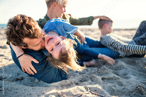 Young family with two small children lying down outdoors on beach. photo