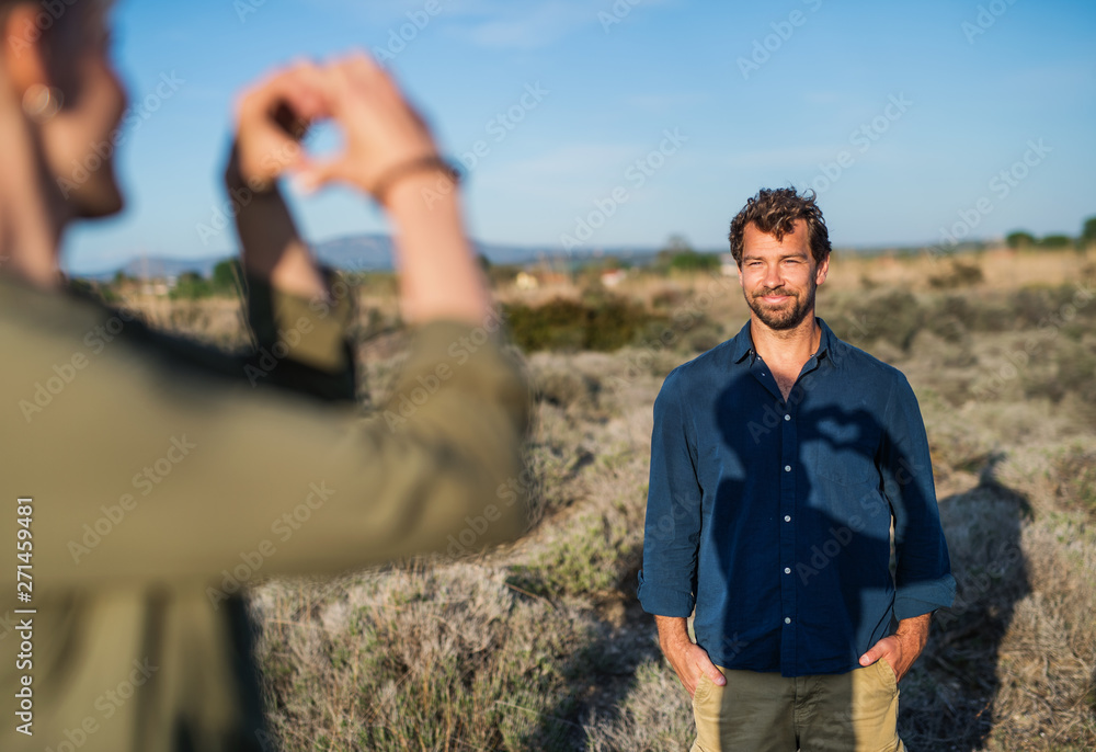 Young affectionate couple standing outdoors in olive orchard, hugging.