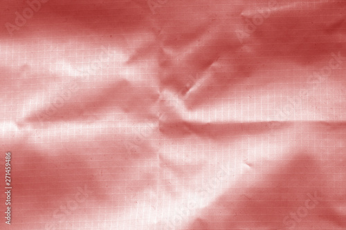 Crumpled transparent plastic surface in red color.