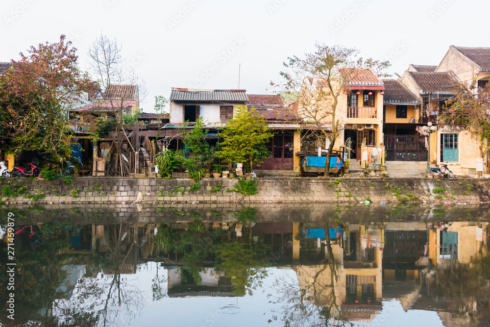 Houses on the bank of the Hoi An river are reflected in the still water, Hoi An, Vietnam