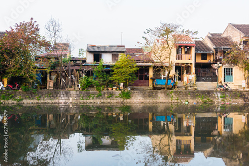 Houses on the bank of the Hoi An river are reflected in the still water, Hoi An, Vietnam