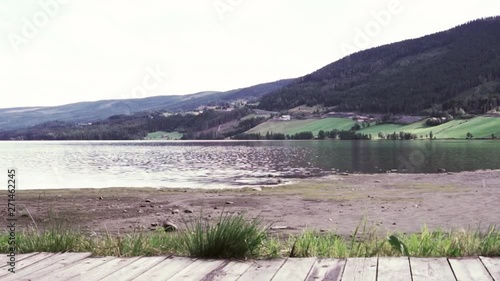 Relaxing nature recreation on an empty beach with sand, grass and planks to sit and enjoy the ocean and mountain view on a quiet, warm summer day, with zoom