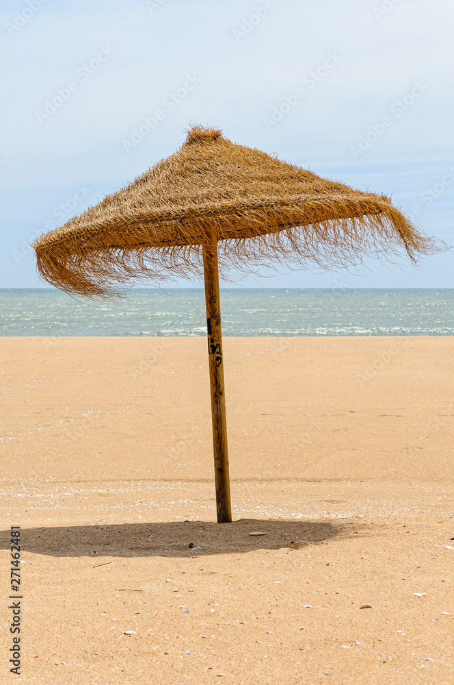 Straw parasol on a sandy beach.