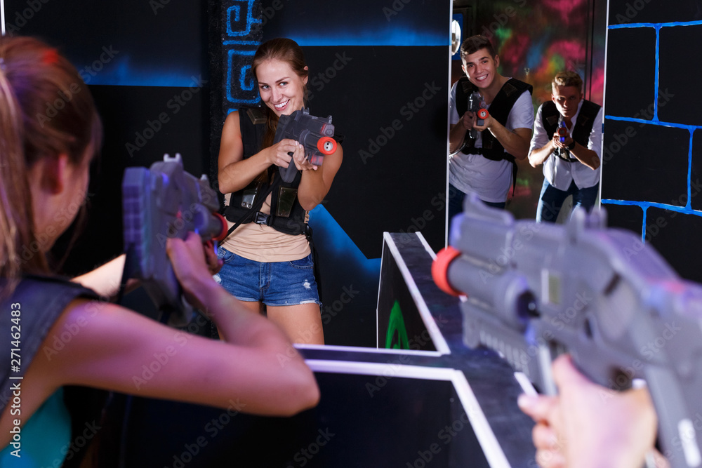 Excited people playing enthusiastically laser tag game
