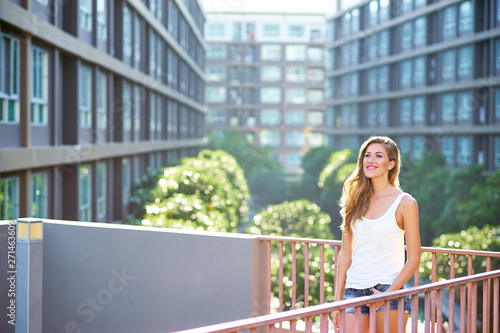 Summer in the city. Pretty young woman against condominium building.