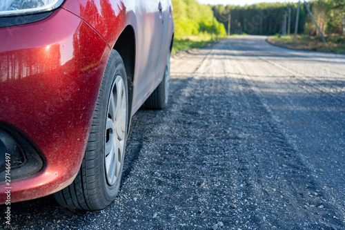 Dusty cars on a country road  small rubble on the road. Close up of car tires on dirt country road in summer afternoon