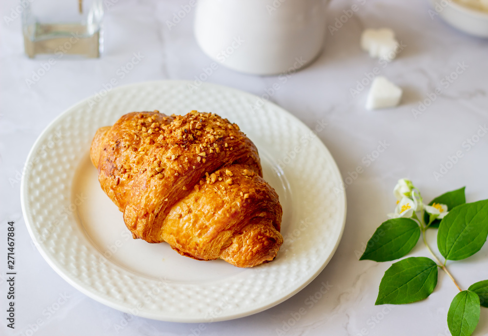 A croissant and coffee on a marble background. The flowers. Breakfast. A croissant and coffee on a marble background. The flowers. Breakfast.