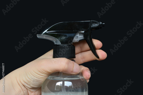 Small female hand holding spray bottle cleaner on black background photo