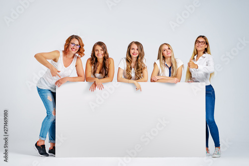 Advertising. Your text here. Group of pretty young women holding an empty board with copy space together on white background.