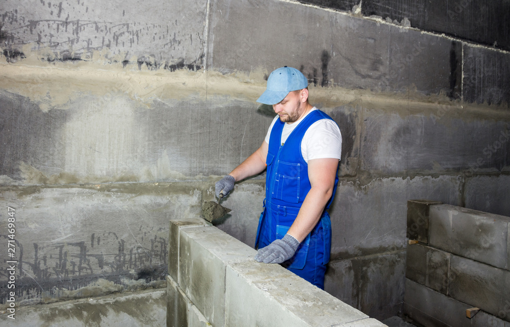 Industrial worker using trowel and tools for building exterior walls with blocks and mortar Industrial worker using trowel and tools for building exterior walls with blocks and mortar