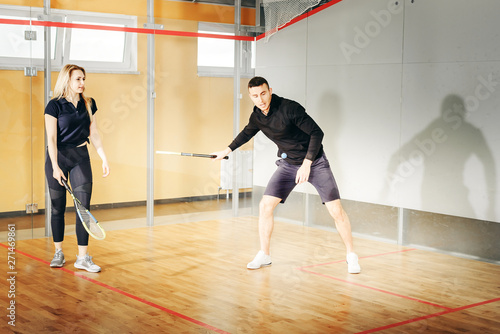 athletic man and woman playing squash.