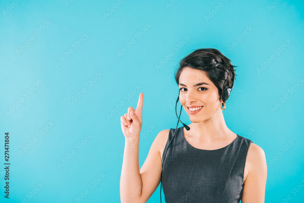Fototapeta premium cheerful mixed race call center operator in headset showing idea sign isolated on blue