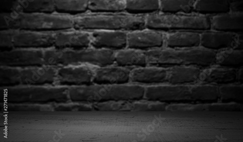 Old wood table with blurred concrete block wall in dark room background. © kishivan