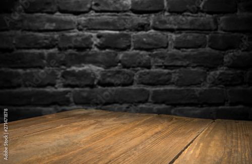 Fototapeta Naklejka Na Ścianę i Meble -  Old wood table with blurred concrete block wall in dark room background.
