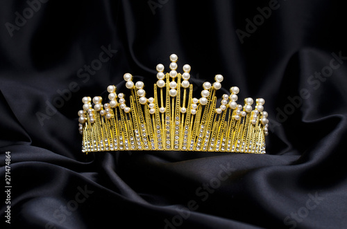 golden crown with pearls and diamonds isolated on black silk