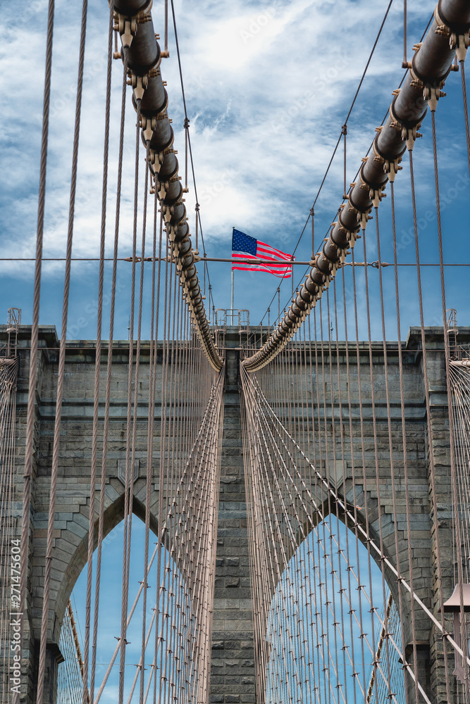 Obraz premium Brooklyn Bridge, New York City. American Flag, Cloudy Blue Sky, Vertical Banner