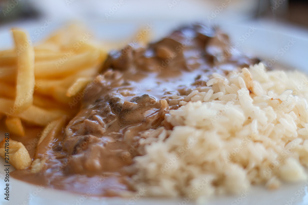 Single course with pork filet with mushrooms sauce, chips and rice. Single course with pork filet with mushrooms sauce, chips and rice.