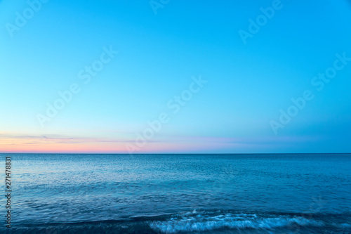  Waving sea water on a sunset against a blue sky. Copy space. 