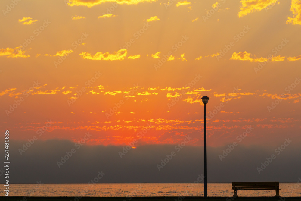 street lamp and bench in front of the beautiful bright red sunset