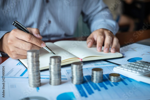 Businessman accountant counting money and making notes at report doing finances and calculate about cost of investment and analyzing financial data, Financing Accounting Banking Concept