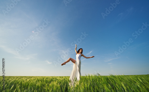 Yoga and fit. Flying dancer in the air. Happy woman ballerina in white fabric skirt posing on Green field. Summer or concept © oes