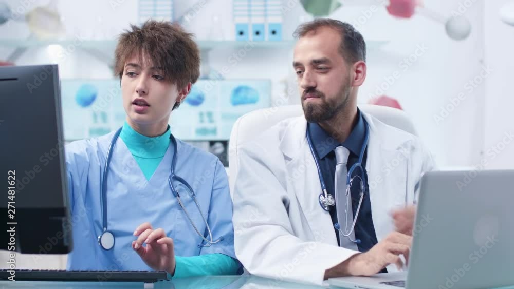 Physician explaining something to a student nurse. In the background - a modern and high end office or research center Physician explaining something to a student nurse. In the background - a modern and high end office or research center