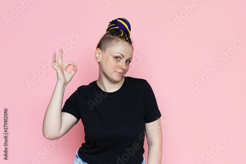 Portrait of woman with a variety of emotions on the face. Standing over pink background. Woman has dreadlocks on her head, she has freckles on her face.